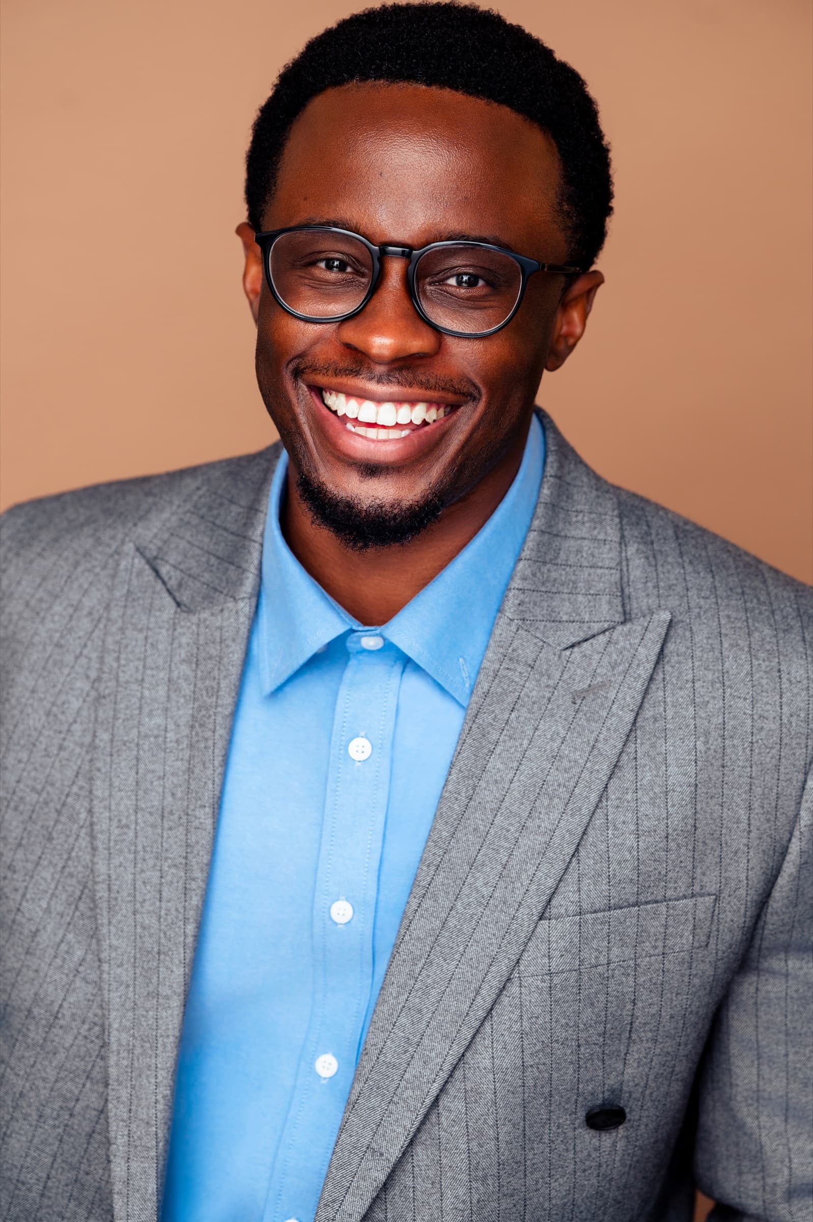Lanre Adigun headshot — grey pinstripe suit